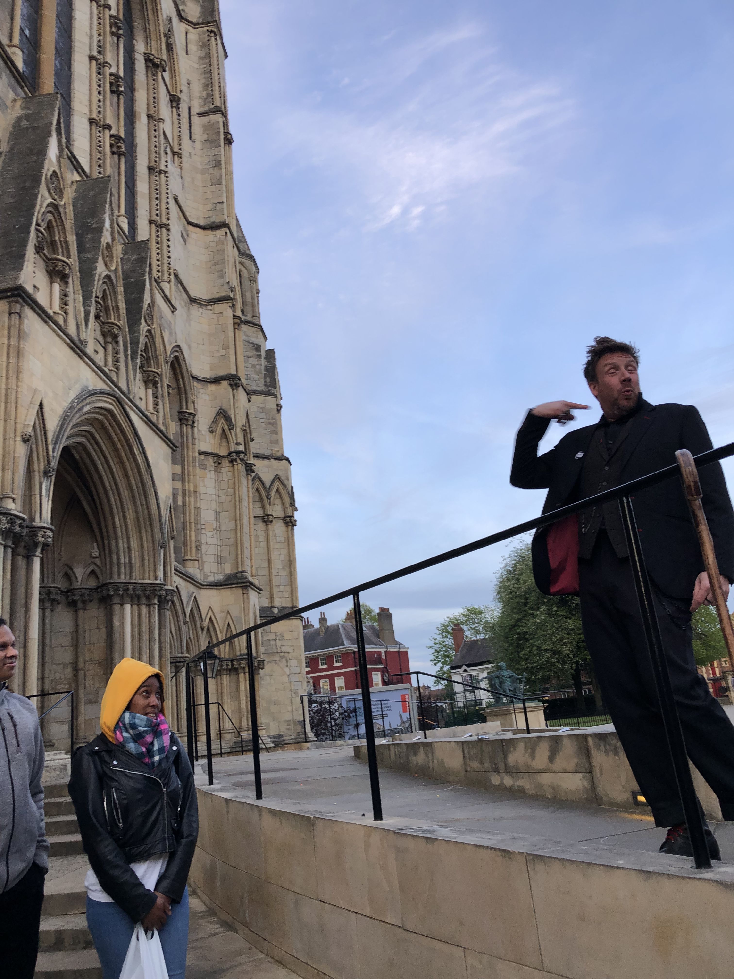 Dorian Deathly stands high above his tour group. Set against the blue sky as a background, next to York's Minster
