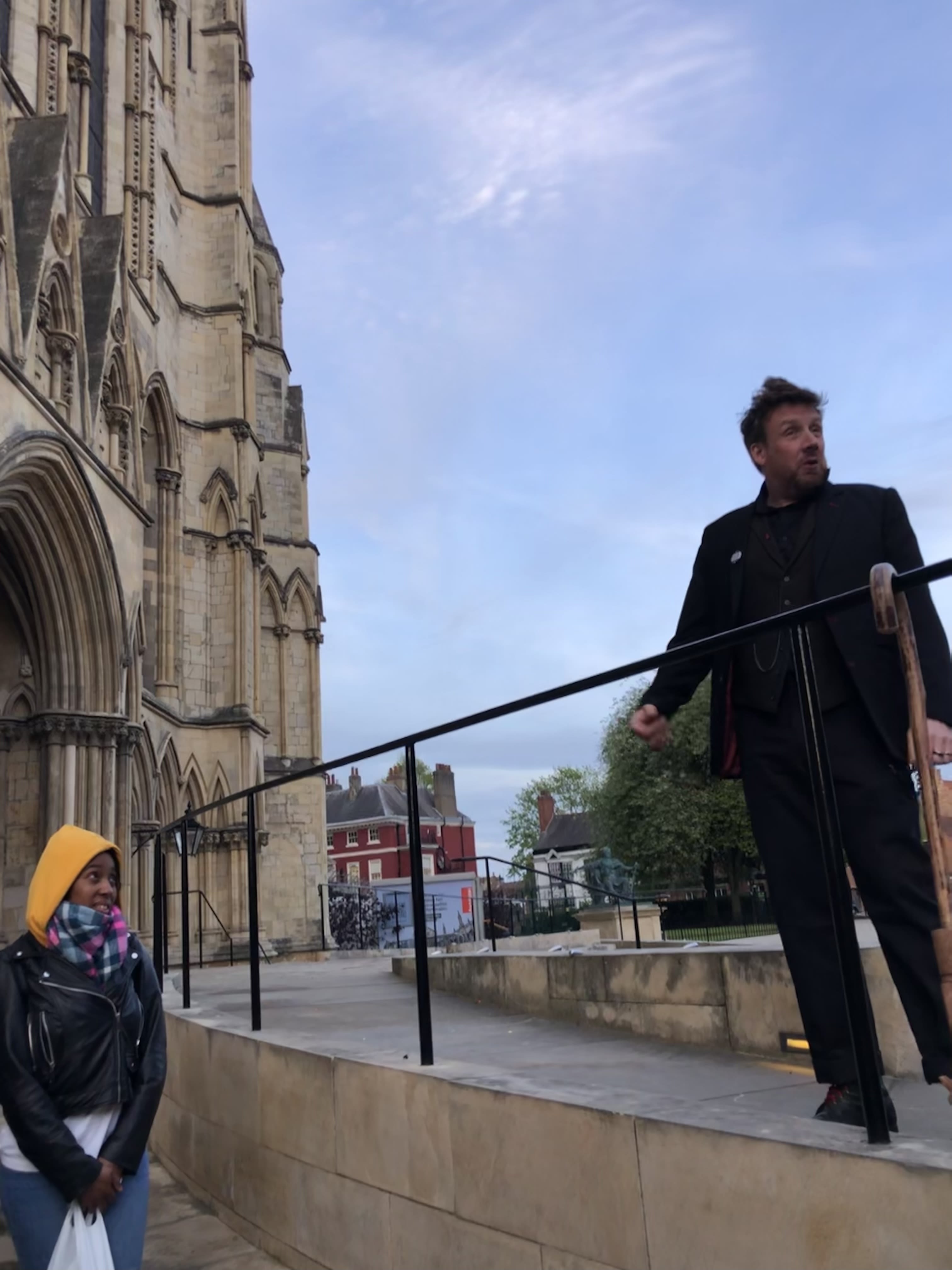 Dorian Deathly stands high above his tour group. Set against the blue sky as a background, next to York's Minster