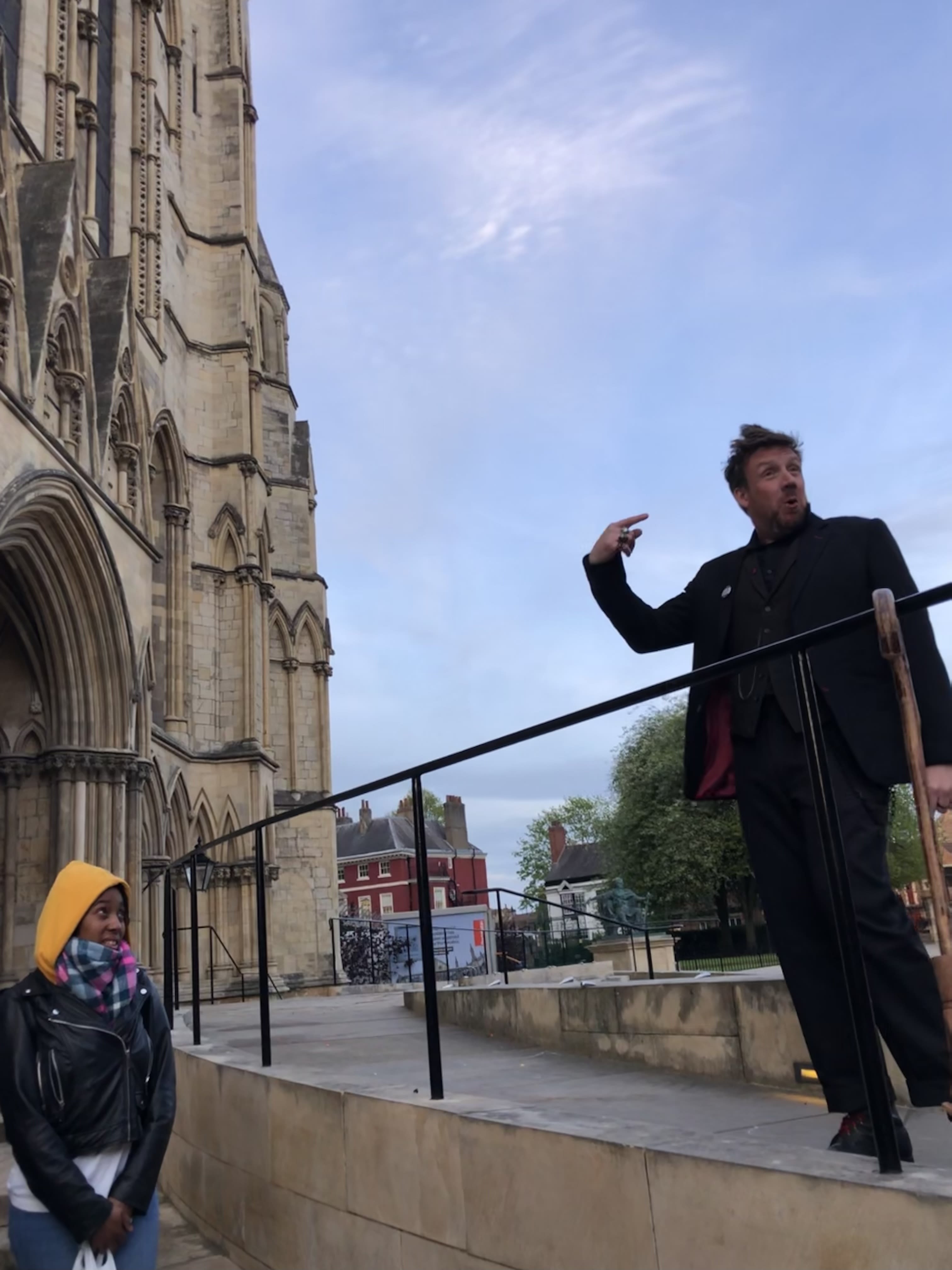 Dorian Deathly stands high above his tour group. Set against the blue sky as a background, next to York's Minster