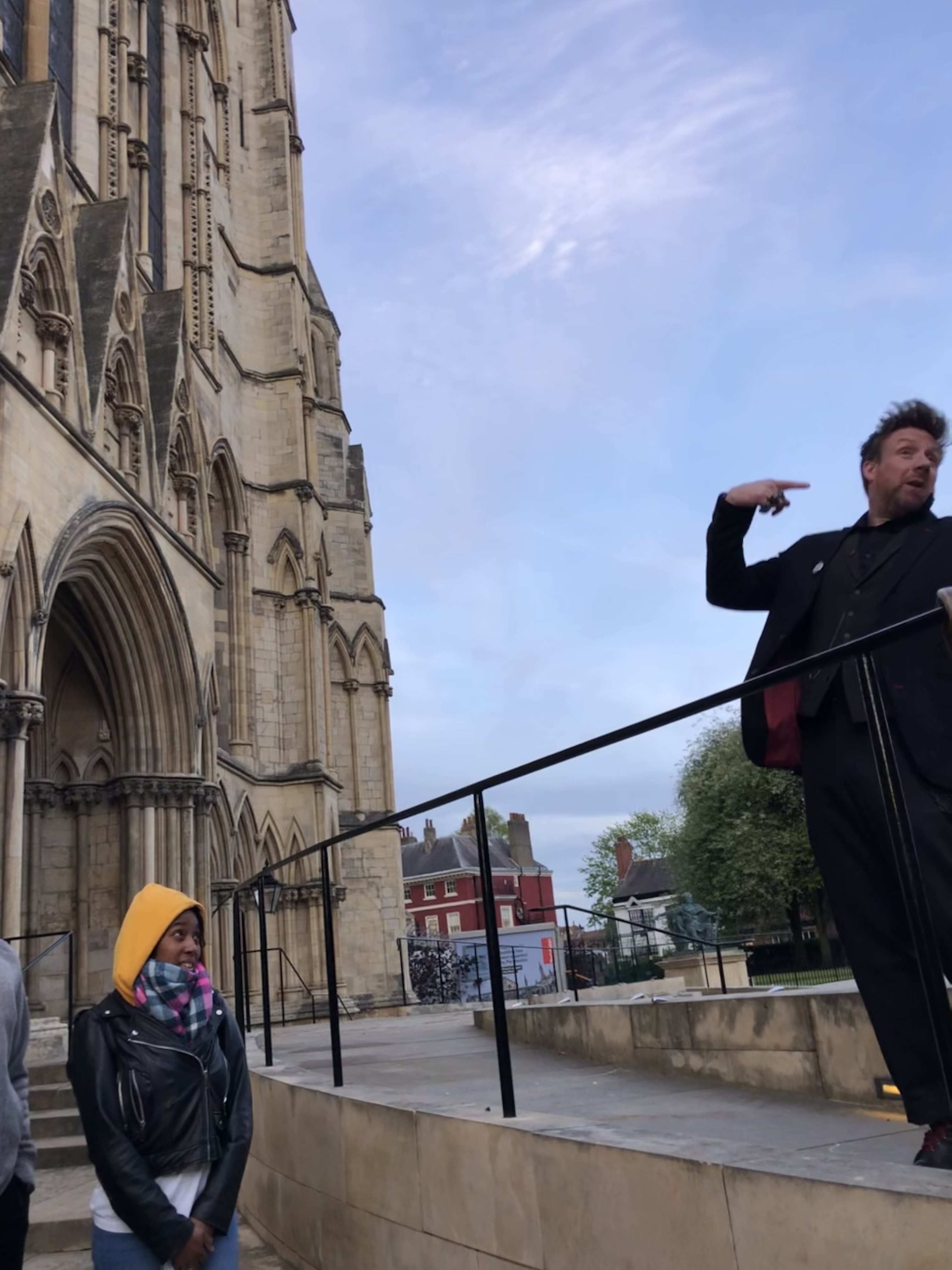 Dorian Deathly stands high above his tour group. Set against the blue sky as a background, next to York's Minster