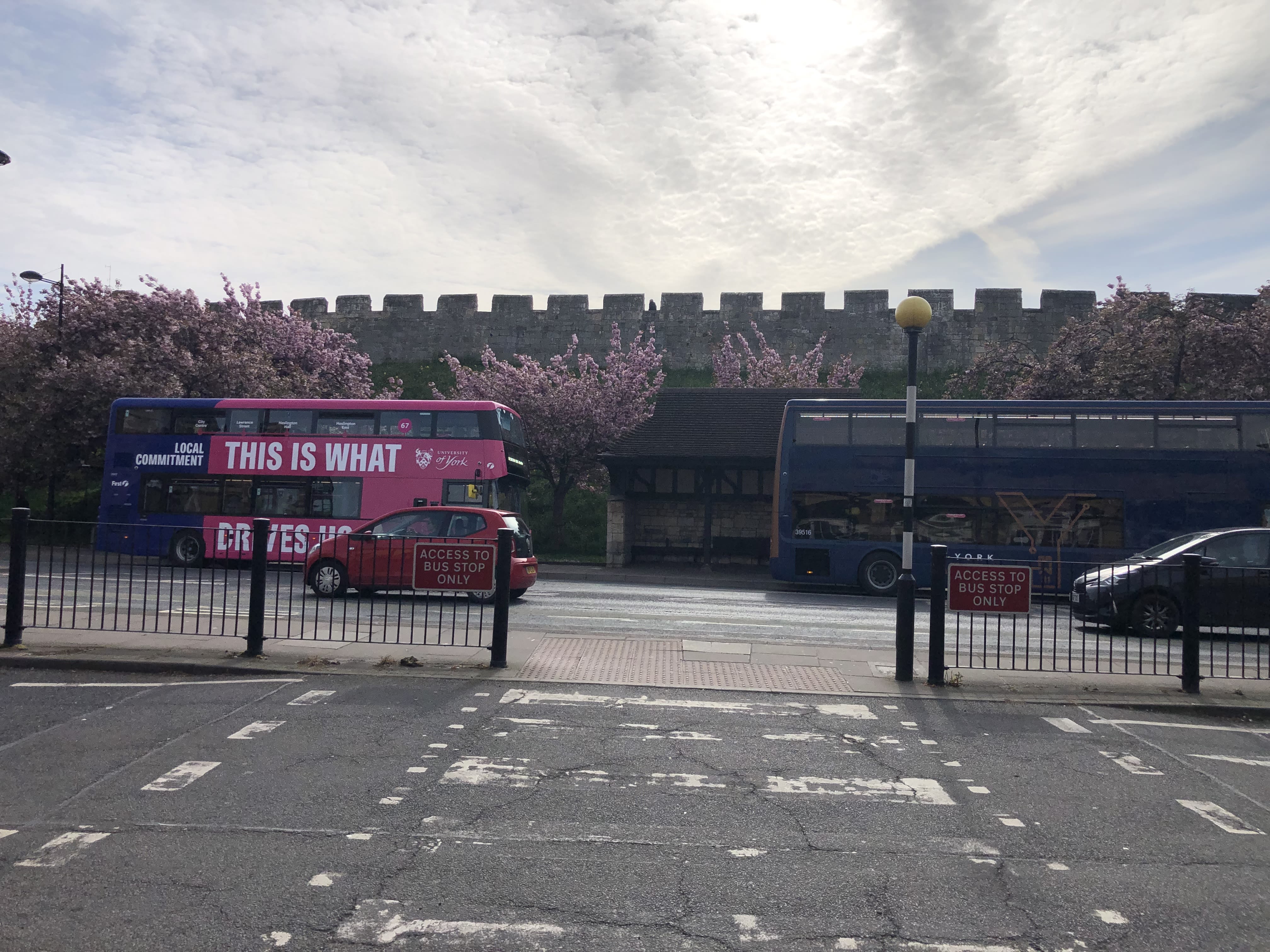 Cars and busses are seen juxtaposing the ancient walls behind them