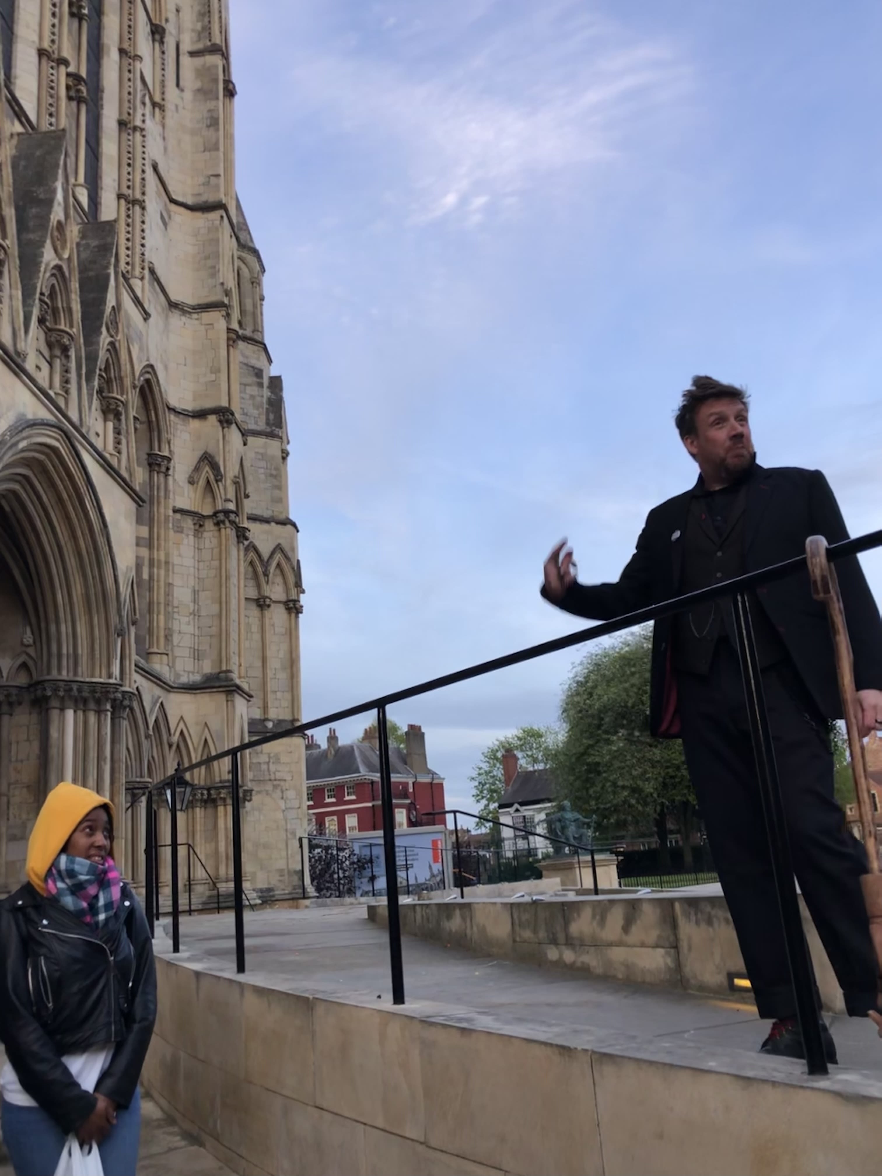 Dorian Deathly stands high above his tour group. Set against the blue sky as a background, next to York's Minster